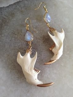 a pair of white and gold earrings on top of a piece of ice covered ground