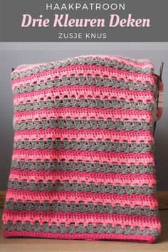 a pink and gray crocheted blanket sitting on top of a table