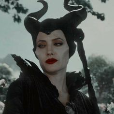 the maleficent character is dressed in black with horns on her head and red lips