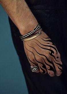 a man's hand with tattoos on it and two bracelets around his wrist