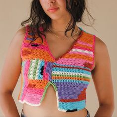 a woman wearing a colorful crochet top with her hands on her hips and looking at the camera