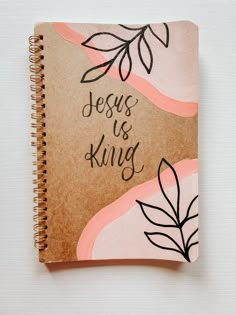 a spiral notebook with the words jesus is king written on it and leaves drawn on top