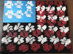 an american flag made out of red, white and blue flowers with paw prints on it