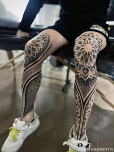 a person sitting in a chair with tattoos on their legs