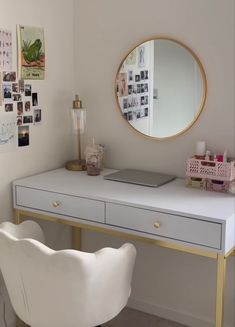 a white desk with a mirror, chair and pictures on the wall