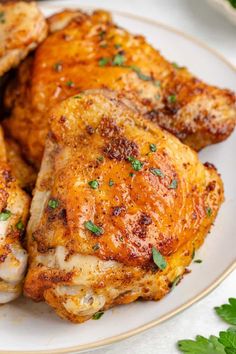 some chicken on a plate with parsley and seasoning sprig next to it