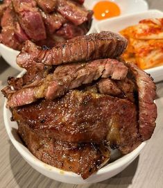 some meat is sitting in a bowl on a table with other food and condiments