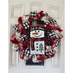 a christmas wreath with a snowman on it hanging from the side of a door