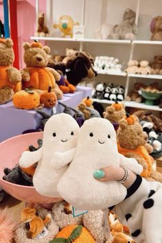 two stuffed animals sitting on top of each other in front of a bowl filled with pumpkins