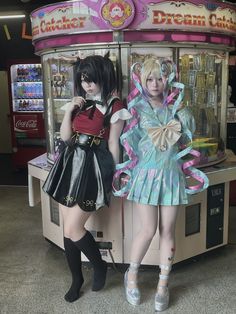 two women in costumes standing next to a machine