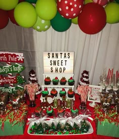 a christmas themed dessert table with santa's sweet shop sign and candy bar decorations