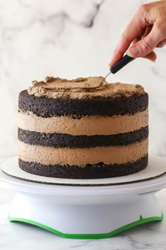 a person is cutting into a chocolate cake with a knife on a white platter