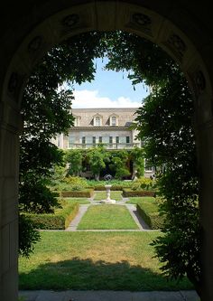 an archway leading into a formal garden with hedges