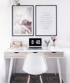 a white desk with a laptop computer on it and two pictures hanging above the desk