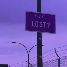 a purple sign that says are you lost? on the side of a fenced in area