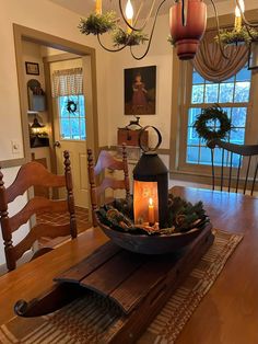 a dining room table with a candle on the centerpiece and wreaths hanging from the ceiling