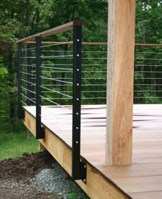 a wooden deck with black iron railings and wood slats on the bottom level