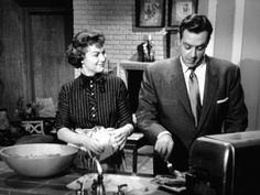 a man and woman are standing in front of a counter top with food on it