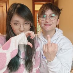 a man and woman posing for the camera in front of a bed with pink hearts on it