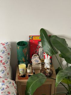 a table with some plants and other items on it next to a bed in a room