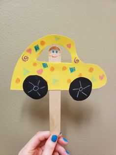 a person holding up a paper car on a stick