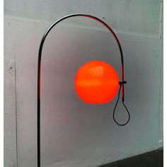 an orange light is hanging on the side of a wall next to a black lamp