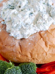 a close up of a bread bowl with broccoli on the side and white sauce in it