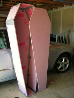 a white car parked in a garage next to a tall pink object that looks like a surfboard