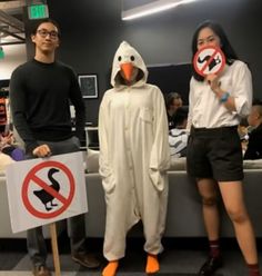 three people dressed in costumes standing next to each other holding signs that say no ducks