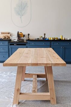 a wooden table sitting in the middle of a kitchen with blue cabinets and counter tops