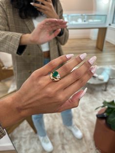 the woman is wearing a ring with a green stone on it's middle finger