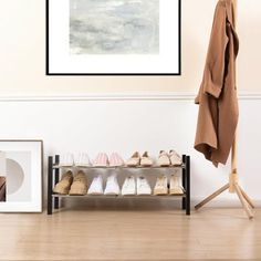 shoes are lined up on a shelf in front of a coat rack and framed photograph