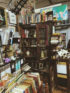 a room filled with lots of books next to a wall covered in pictures and paintings