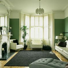 a living room with green walls and white furniture