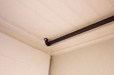 a black pipe is hanging from the ceiling above a toilet paper dispenser