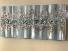 a painting hanging on the wall with silver and gold paint splattered over it