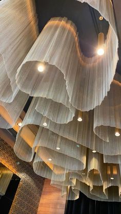 the lights are hanging from the ceiling in the building's lobby, which is decorated with layers of sheer fabric