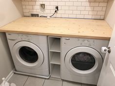 a washer and dryer in a small room with tile flooring on the walls