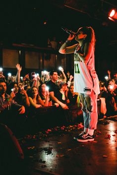 a man standing on top of a stage holding a microphone in front of a crowd