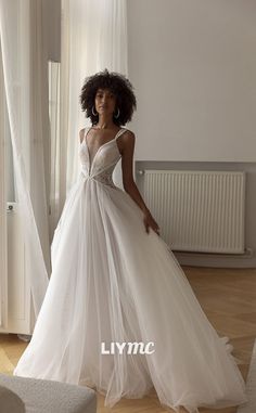 a woman in a white wedding dress standing next to a window with her hand on her hip