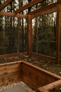 the inside of a chicken coop with rocks and gravel on the ground in front of trees