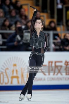 a woman skating on an ice rink with her arms in the air and one hand up