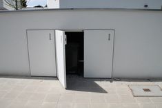 an open white door on the side of a building with no doors and only one person standing in it