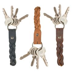 three keys are attached to the ends of two leather keychains with braiding