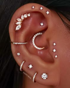 an ear with several different types of piercings on it, including stars and moon