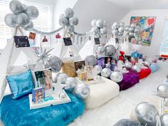 a room filled with lots of silver balloons and pictures on the wall next to a bed