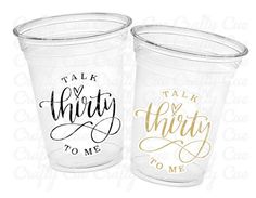 two clear plastic cups with gold foil lettering on them, one says talk thirty to me and the other says talk thirty to me