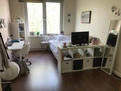 a bedroom with a bed, desk and computer on top of the dresser next to a window