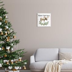 a living room with a christmas tree, couch and wall hanging on the wall next to it