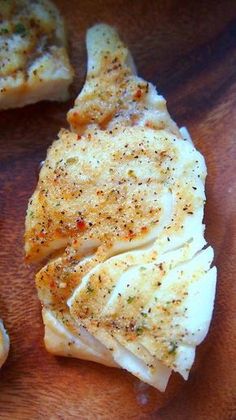 some kind of food sitting on top of a wooden cutting board with seasoning sprinkled on it